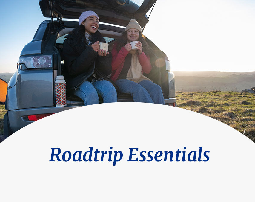 Roadtrip Essentials - two friends drinking tea at the back of an open car trunk.