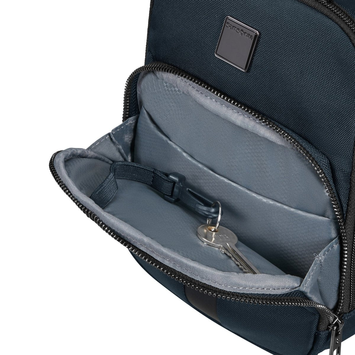 The Samsonite SackSquare Crossbody Small backpack by Samsonite offers hands-free mobility in a fashionable dark green design, complete with an open front pocket that reveals a set of silver keys on a key holder inside.