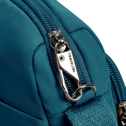 Close-up of a capri blue Travelon Roam Anti-theft East/West Crossbody with silver zipper lock and anti-theft clip.