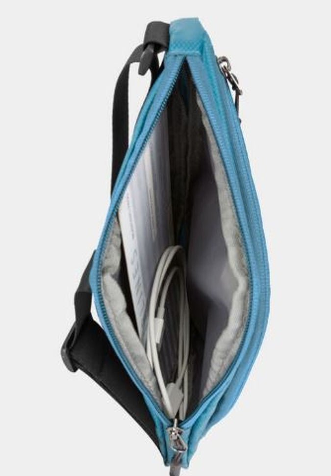 Viewed from above, the open Travelon World Travel Essentials Slim Crossbody Bag, a must-have for travelers, reveals a document and a coiled cable nestled within its interior.