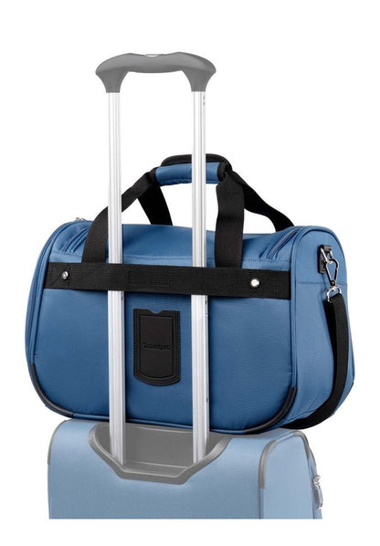 A Travelpro® Maxlite® 5 Soft Tote with black straps is secured on top of a rolling suitcase. This compact travel bag, available in blue, has a slot allowing it to fit over the suitcase's handle, making it the perfect under-seat carry-on.