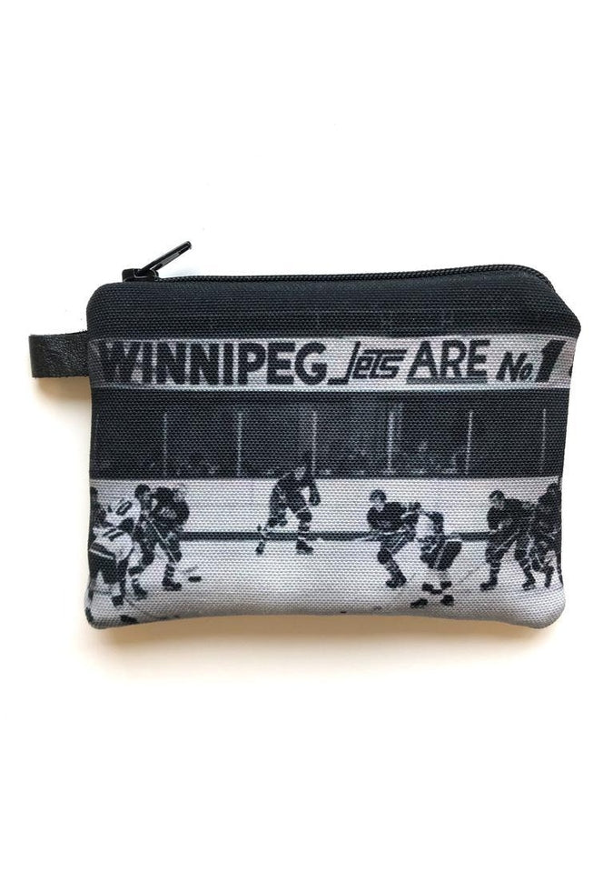 This interlined black and white coin purse from Winnipeg North of Fargo highlights a dynamic hockey game scene with players on the ice and a bold sign declaring "Winnipeg Jets ARE No. 1." It's perfect for securely holding your loose change or earbuds while proudly displaying your team spirit.