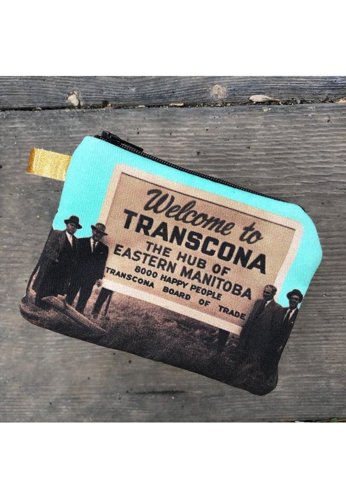 Cosmetic bag from Winnipeg North of Fargo showcases an image of five men gathered around a sign reading, "Welcome to Transcona, The Hub of Eastern Manitoba." This durable interlined accessory is ideal for storing earbuds or small coin purses and is part of the Winnipeg North of Fargo Coin Purses collection featuring five prints.